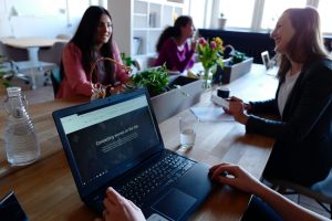 mujeres platicando en una mesa mientras trabajan 